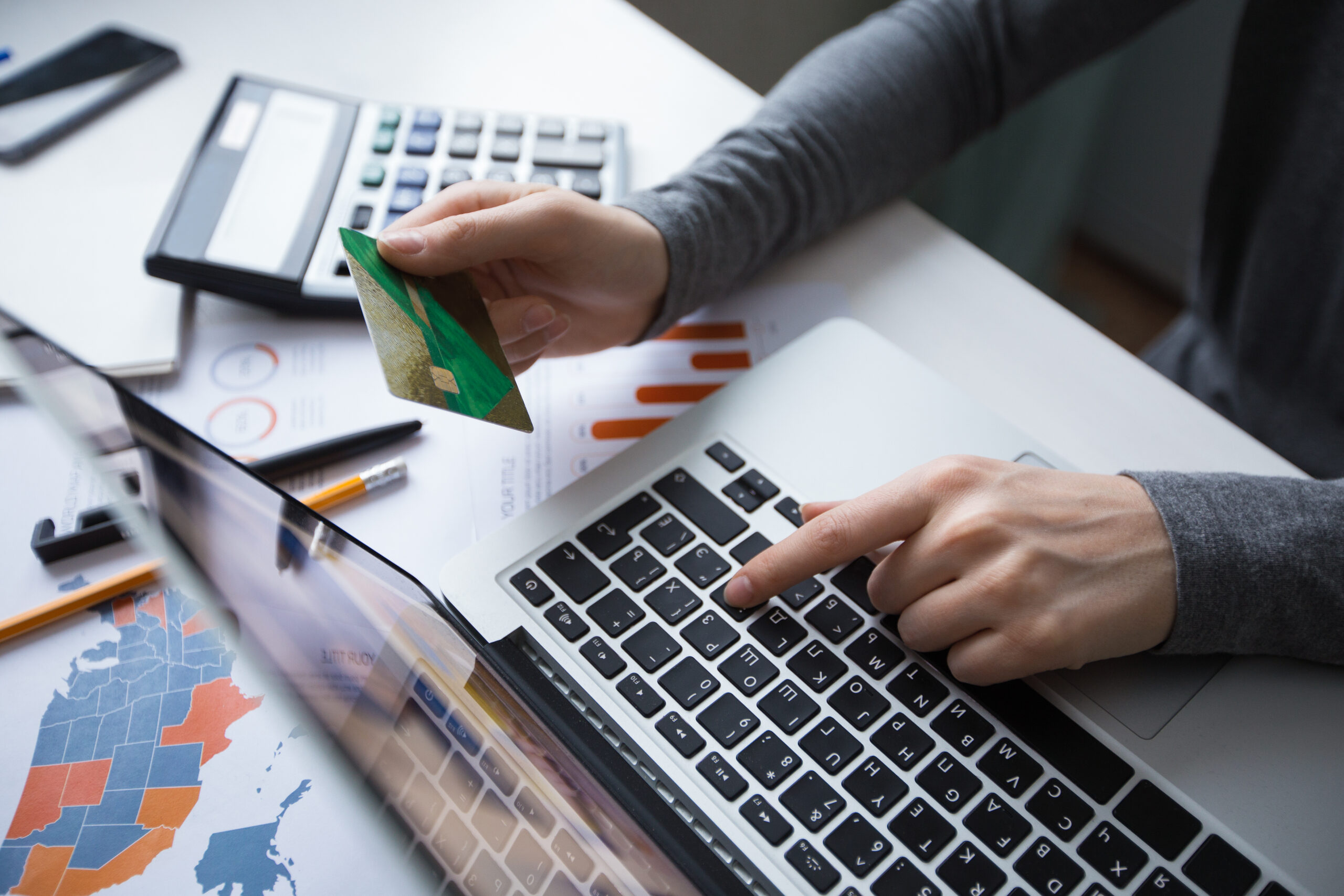 Cropped view of business person working on laptop computer, holding credit card and doing online banking